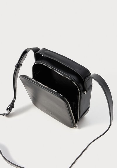Borsa a tracolla in pelle nera, dalla forma rettangolare, con scomparti con zip e tracolla regolabile. Texture liscia con dettagli di design minimalista.