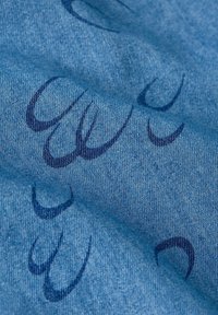 Blått tyg med denimstruktur och subtila mörkblå svängande mönster. Materialet verkar mjukt och något skrynkligt.