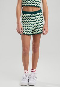 Vihreä-valkoinen aaltoilevakuviollinen crop-top ja shortsiyhdistelmä, jossa on hapsureuna, joustava vyötärö ja nyöritysdetaileja.