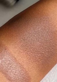 Swatch of foundation on medium-brown skin, featuring a smooth texture and a light matte finish, blending into the natural skin tone.