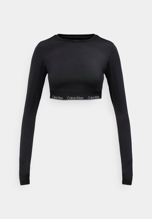 Crop top à manches longues noir en matériau lisse, avec une bande logo en bas. Design simple et ajusté avec un col rond.