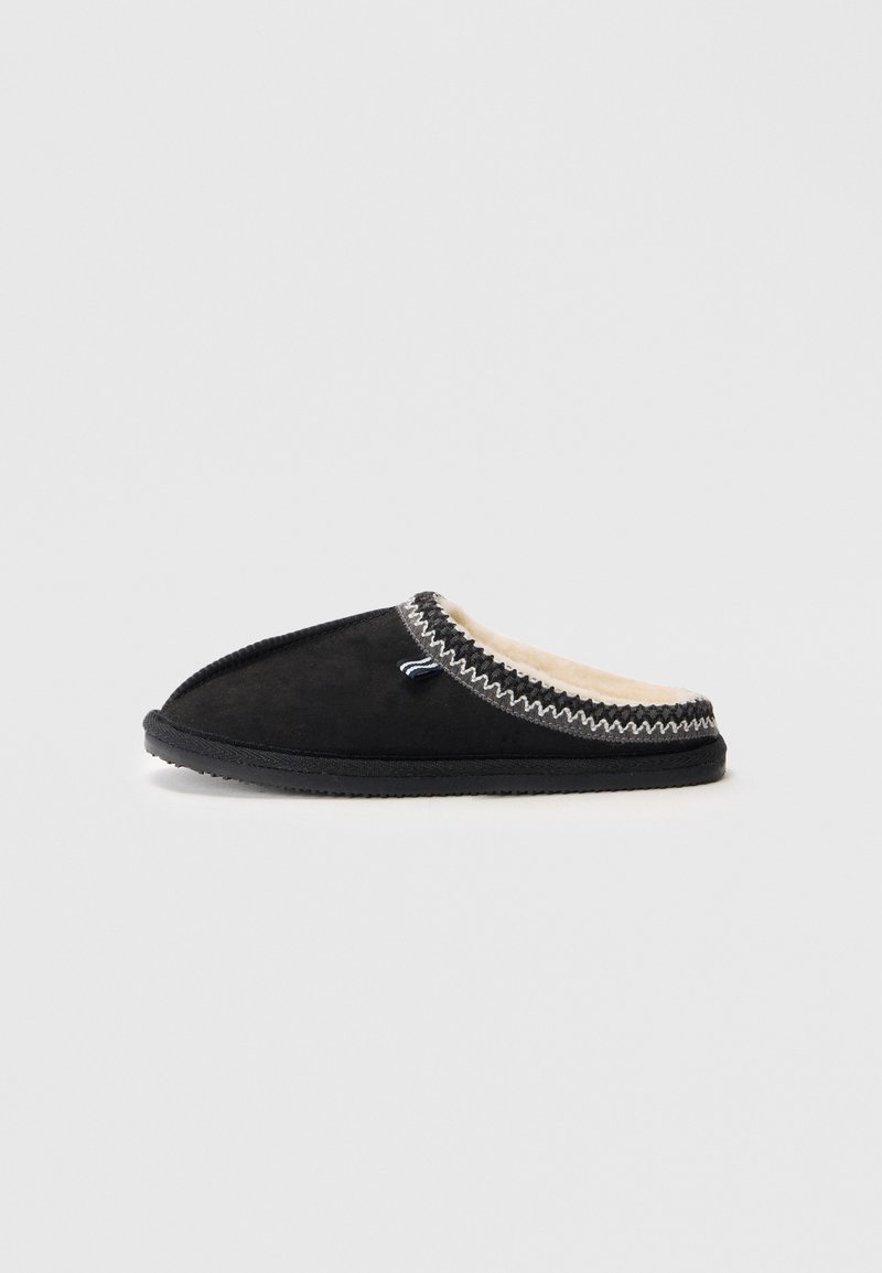 Pantofii din suede negru, cu vârful rotunjit, căptușeala interioară moale și cusături decorative de-a lungul gulerului. Talpă din cauciuc pentru aderență.