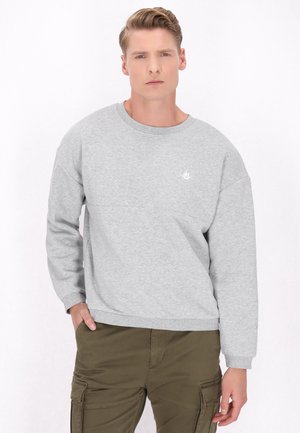 Lys grå sweatshirt med rund halsudskæring, drop-skulder og ribbede manchetter. Har et lille hvidt logo på brystet. Blødt stof.