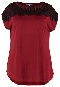Kvinnors kortärmad röd blus med svart spetsdetalj runt halsringningen och axlarna.