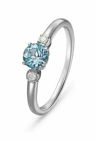Silberring mit einem runden, hellblauen Edelstein in der Mitte, flankiert von zwei kleineren, klaren Steinen, glatter, polierter Ringband.