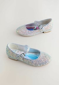 Silberne Glitzer-Ballerinas mit runder Zehenpartie, seitlichem Riemen und Schnalle, ausgestattet mit einem bunten Innensohlenmuster. Strukturierte, funkelnde Oberfläche.