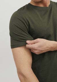 Oliven grøn bomulds t-shirt med rund hals, korte ærmer og en tætsiddende pasform, der viser tekstur gennem stoffet.