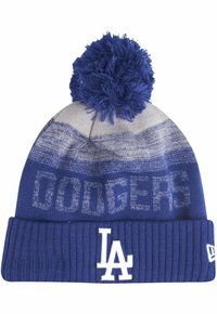 Gorro de punto azul con un puño acanalado texturizado. Presenta una parte superior con un patrón y un gran pompón azul. En la parte delantera se muestra "DODGERS" y el logo "LA" en blanco.