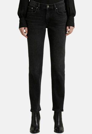 Jeans in denim nero con vestibilità slim, dotati di cinque tasche, chiusura con bottone e leggere sfumature. Abbinati a stivali alla caviglia.