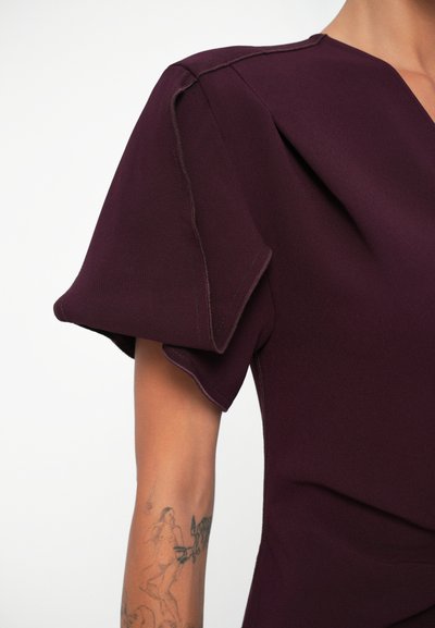 Mauve dress with puff sleeves, featuring a v-neck design and visible stitching accents on the fabric. Smooth texture, structured shape.
