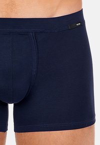 Marineblauwe boxershorts gemaakt van zachte stof met een snug fit, voorzien van een gebrandmerkte tailleband en een glad, minimalistisch ontwerp.
