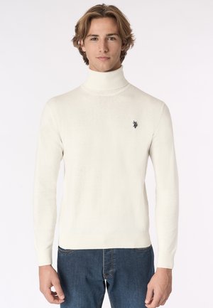Maglione bianco a collo alto con polsini e fondo a coste. Presenta un piccolo logo nero sul lato sinistro del petto. Tessuto morbido, design aderente.
