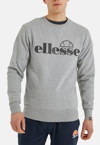 Grauer Pullover aus Baumwollmischung, mit großem schwarzen "ellesse"-Logo. Rippbündchen und -saum sowie runder Ausschnitt.