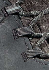 Svart atletisk skoöverdel som har textila och syntetiska material, strukturerad yta, grå snören och platta, vävda snöröglor.