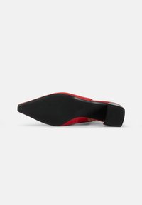 Red high-heel shoe with a pointed toe, smooth leather upper, textured black sole, and a modest block heel for stability.