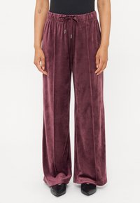 Pantaloni din catifea, cu croi larg, de culoare burgundă închisă, cu talie elastică și șnur reglabil. Textură fină, cu o potrivire lejeră.
