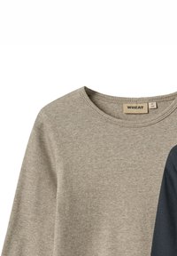 Chemise à manches longues grise à rayures avec une accentuation bleu foncé sur un côté. Le tissu est doux, avec un col rond et une étiquette affichant les informations de la marque.