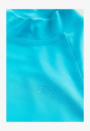 Türkise Sportoberteil mit hohem Kragen, nahtlosem Design und dezentem eingraviertem Logo. Glatte Textur und leichtes Material.