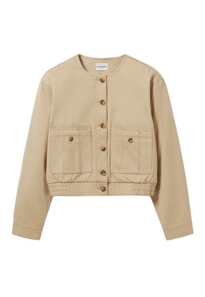 Veste cropped beige avec un col rond, un devant à boutons et deux poches poitrine. Dispose d'une taille élastique et d'une texture de tissu lisse.