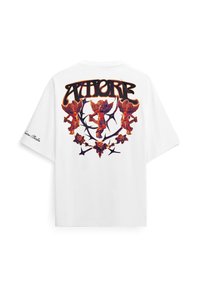 Maglietta bianca oversize con tre cherubini arancioni, rami spinosi neri e rose stampati sulla schiena, e testo corsivo sulla manica sinistra.