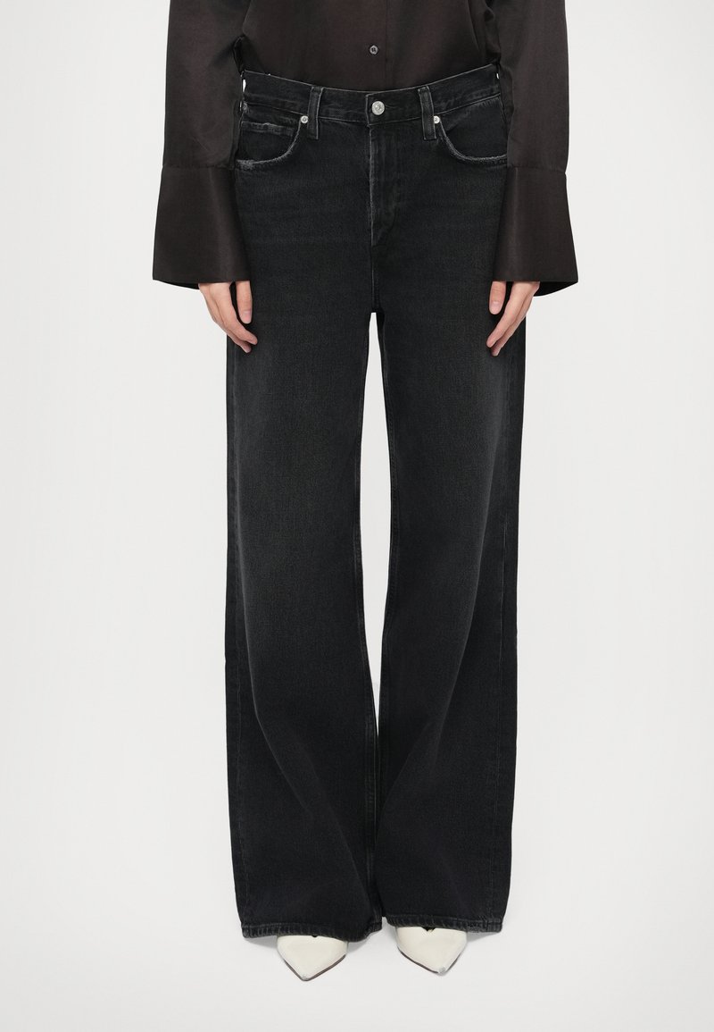 Μαύρα τζιν με φαρδιά μπατζάκια από τζιν ύφασμα. Δ�ιαθέτουν πέντε τσέπες, κλείσιμο με κουμπί και φερμουάρ, και καθαρή, λεία υφή.