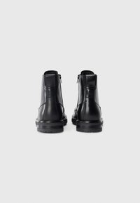 Black leather ankle boots featuring a sleek design with a smooth texture, rear zipper closures, and a sturdy black rubber sole.