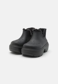 Crne slip-on cipele s teksturiranim završetkom, koje imaju mekan, umjetni krzneni oblog i prozračne rupice na gornjem dijelu za prozračnost.