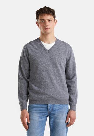 Maglione grigio a v-neck realizzato in tessuto morbido, con maniche lunghe e vestibilità regolare, abbinato a jeans azzurri chiari.