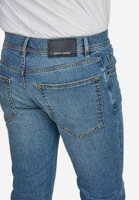 Denim jeans in medium blue met een getailleerde pasvorm, met achterzakken, contrasterende stiksels en een zwart leren logo patch op de tailleband.