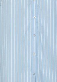 Camicetta azzurra chiaro con bottoni, caratterizzata da righe verticali bianche, realizzata in un tessuto morbido con una texture liscia e cinque chiusure a bottone.