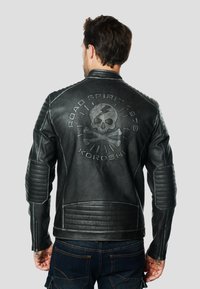 Zwarte leren motorjas met doorgestikte accenten op schouders en mouwen, met een ontwerp van een doodskop en botten op de rug.