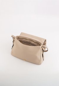 Beżowa skórzana torebka z teksturowaną powierzchnią, z zamkiem błyskawicznym na górze i złotymi akcentami. Widoczne wnętrza z przegródkami, w tym mniejsza zamykana sekcja.