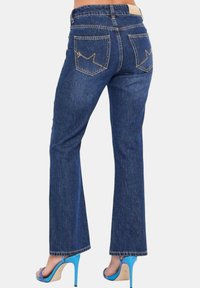 Jeans svasati di un blu scuro con una texture liscia, dotati di tasche posteriori con cuciture a zigzag e un design a vita bassa.