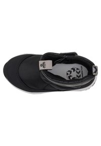 Svart sportskor med en strukturerad ovandel, rund tå, kardborreband och vit sula. Har logotyp på hälen och inre mönster.