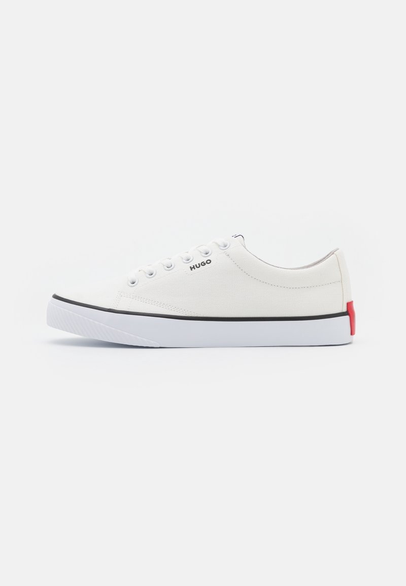 Basket basse en toile blanche avec lacets blancs, bordure noire sur la semelle, détail rouge au talon et logo "HUGO" sur le côté.