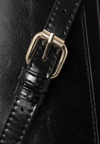 Correa de bolsa de cuero negra con un brillante hebilla de metal dorado, con un acabado texturizado y detalles cosidos, que destacan la durabilidad y el diseño.