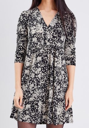 Robe noire à fleurs avec décolleté en V, manches trois-quarts et ourlet à volants ornée d'un motif de fleurs crème clair.