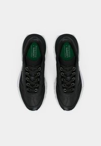 Μαύρα αθλητικά παπούτσια με δερμάτινο επάνω μέρος με υφή, ανακλαστικές λεπτομέρειες και στρογγυλά κορδόνια. Διαθέτουν μαξιλαρωμένη σόλα και πράσινη ετικέτα στο εσωτερικό πάτο.