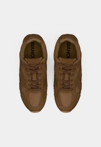 Καφέ αθλητικά παπούτσια από σουέτ και δίχτυ, με υφή στην επάνω επιφάνεια, στρογγυλή μύτη και δέσιμο με κορδόνια μπροστά. Διακριτικό λογότυπο στην εσωτερική σόλα.