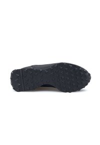 Suola di sneaker nera con una superficie testurizzata. Presenta lugs di trazione prominenti disposti in un pattern triangolare e una sezione del tallone liscia.