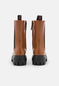 Bottines brillantes brunes avec des panneaux élastiques noirs, semelles en caoutchouc épaisses et une languette; dotées d'une fermeture éclair et d'accents texturés sur les côtés.