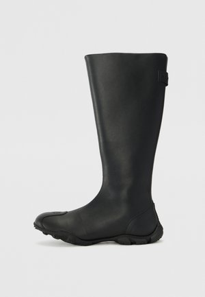 Czarny wodoodporny wysoki botek, wykonany z gładkiego materiału, z okrągłym noskiem, teksturowaną podeszwą i małym akcentem logo po boku.