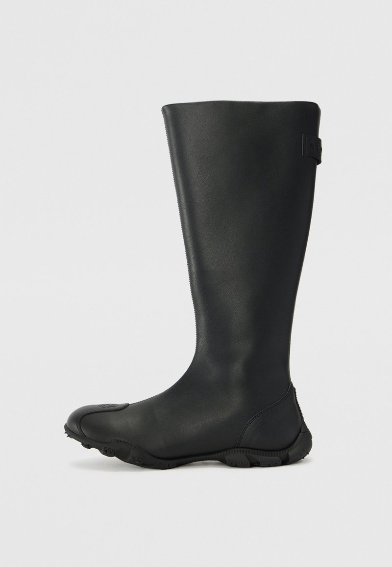 Black waterproof knee-high boot made of smooth material, featuring a rounded toe, textured sole, and a small logo accent on the side.