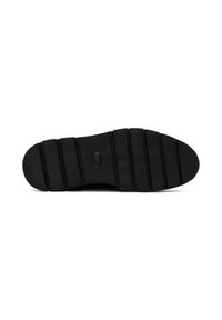Semelle de chaussure en caoutchouc noir avec des rainures horizontales et une surface texturée pour l'adhérence, avec un détail de bouton circulaire près du centre.