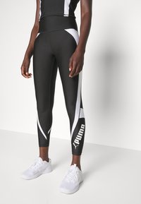 Black athletic leggings with white accents, fitted design, and a logo on the lower leg, made from a smooth, stretchy material.