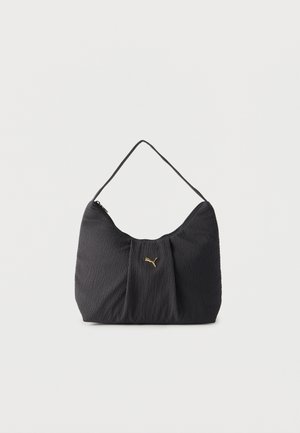 Bolso de hombro negro con textura, pliegues, un solo asa y un pequeño logo dorado de Puma centrado en la parte frontal.