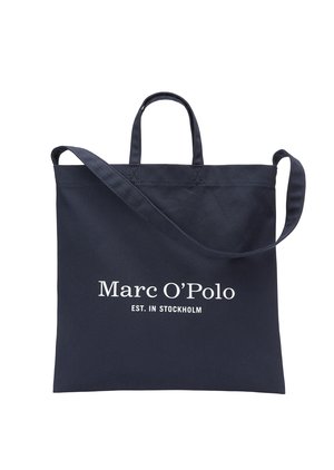 Navyblaue Einkaufstasche mit zwei Griffen, einem verstellbaren Schultergurt und dem Aufdruck "Marc O’Polo EST. IN STOCKHOLM" in Weiß auf der Vorderseite.