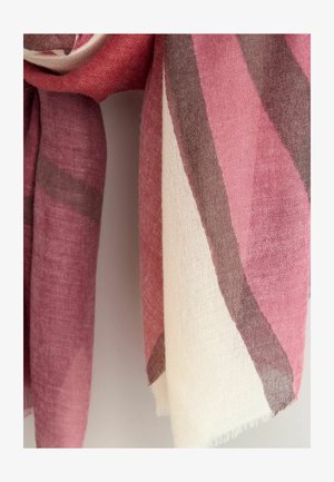 Színes csíkos, rózsaszín, krémszínű és szürke szálakból szövött sál, puha tapintású, rojtos széllel, egy egyszínű háttér előtt lóg.