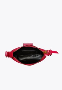 Borsa in pelle verniciata rossa con hardware dorato, chiusura con zip e rivestimento interno nero liscio. Presenta una forma slim e un design elegante.
