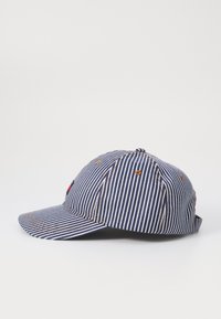 Stripet baseballcap i navy og hvid, med en buet skygge, syningsdetaljer og et lille broderet logo på frontpanelet.